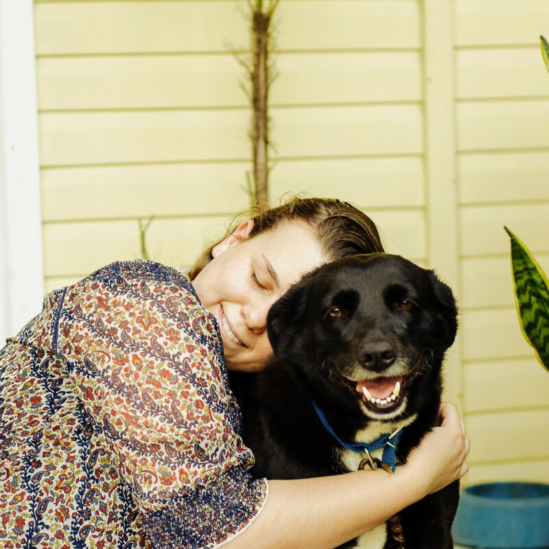 mujer abrazando a su perro negro